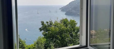 A window with a view of the sea and a distant coastline.