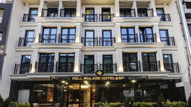 A multi-story hotel with a grand entrance, balconies with ornate railings, and a sign indicating it is a hotel and spa.