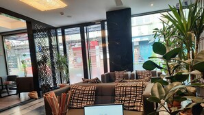 A modern lounge area with a sofa set, a laptop on a small table, and potted plants.