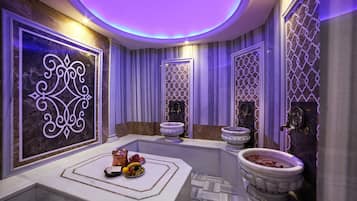 Un baño lujoso con paredes de mármol, un espejo decorativo y un frutero en el tocador.