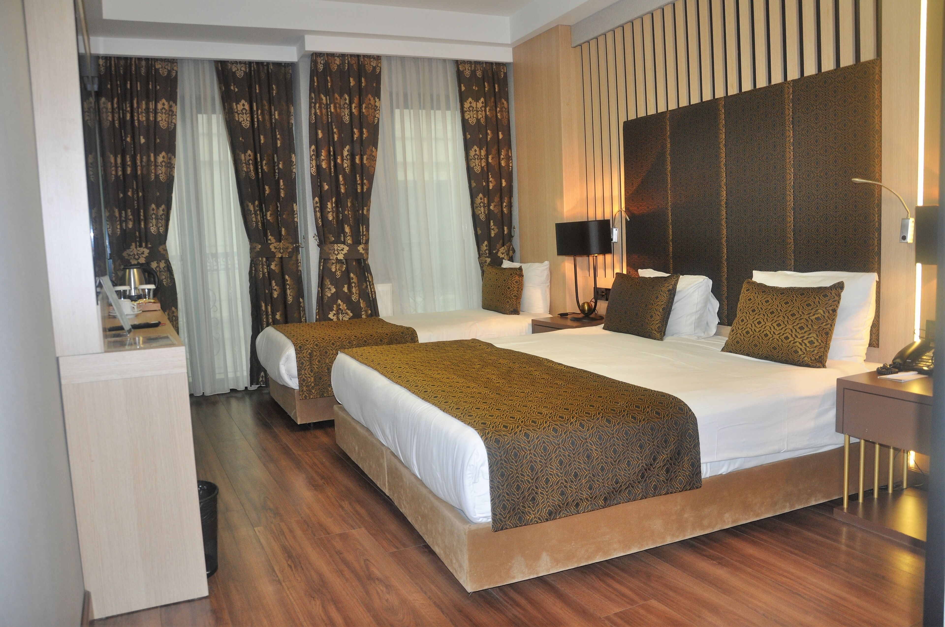 A hotel room with two beds, a desk, and a nightstand.