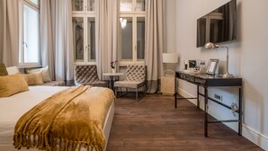 A hotel room with a bed, a desk, a chair, a TV, and a window with curtains. - 29A Guesthouse (Plovdiv)