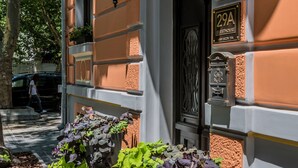 A building with a number '29A' sign, a door with a glass panel, and a planter with purple flowers. - 29A Guesthouse (Plovdiv)