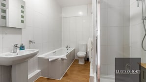 A modern bathroom with a sink, bathtub, toilet, and shower. - City Centre Spacious Apartment (Exeter)