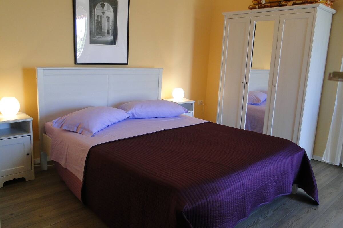 A bedroom with a bed, nightstands, a wardrobe, and a framed picture on the wall.
