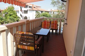 A balcony with a table and chairs, a railing, and a view of buildings and trees.