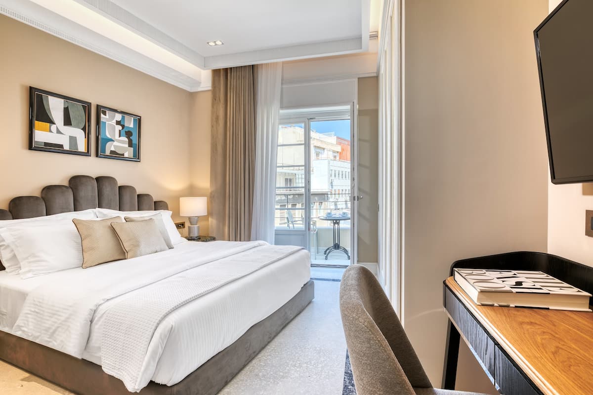 Quarto de hotel com uma cama grande, uma mesa, uma cadeira e uma televisão.