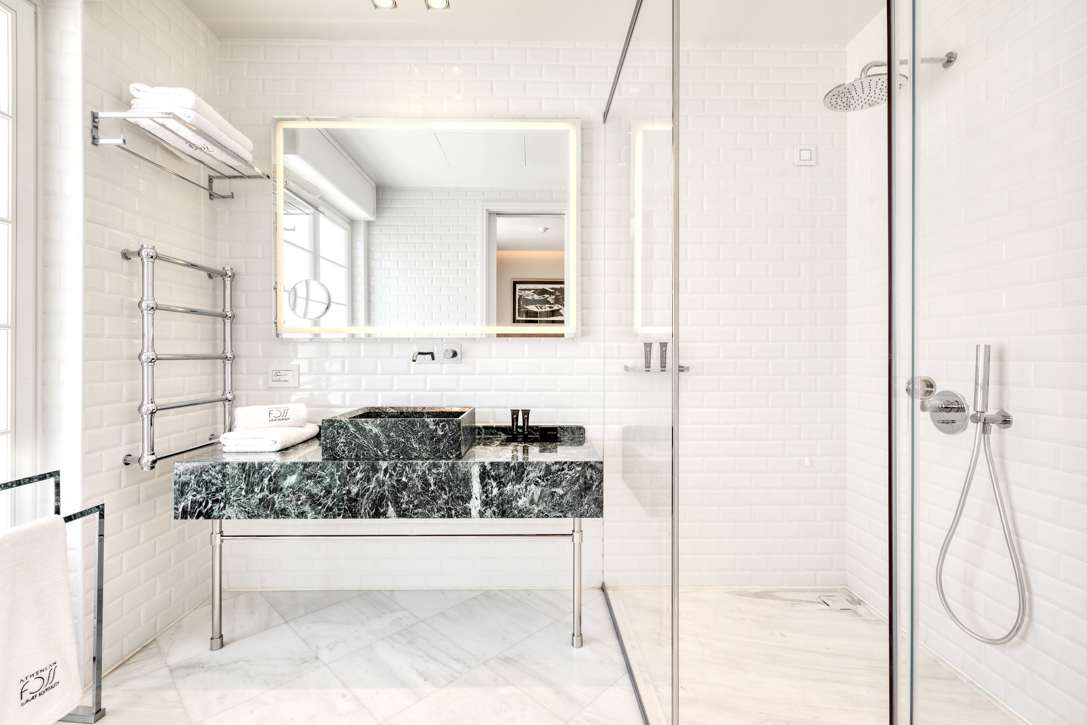 A modern bathroom with a glass shower enclosure, a marble sink, and a large mirror.