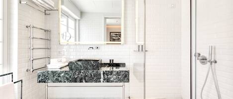 A modern bathroom with a glass shower enclosure, a marble sink, and a large mirror.