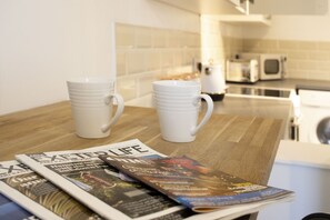 A kitchen counter with two white mugs, a magazine, and a microwave. - Central Exeter Apartment Kimberley Road (Exeter)
