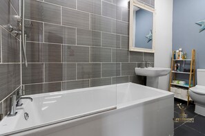 A modern bathroom with a freestanding bathtub, a wall-mounted sink, and a toilet. - Central Exeter Apartment Kimberley Road (Exeter)