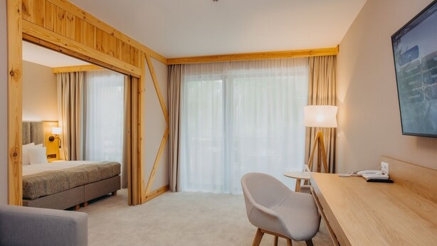 Une chambre d’hôtel comprenant un lit, un bureau, une chaise, une lampe et un téléviseur.
