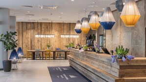 Un espace d’accueil doté d’un mur en bois, d’un comptoir de réception et d’un coin salon avec des chaises et une table.