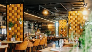 L’intérieur d’un restaurant avec des murs lambrés, des tables et des chaises, et des plantes en pot.