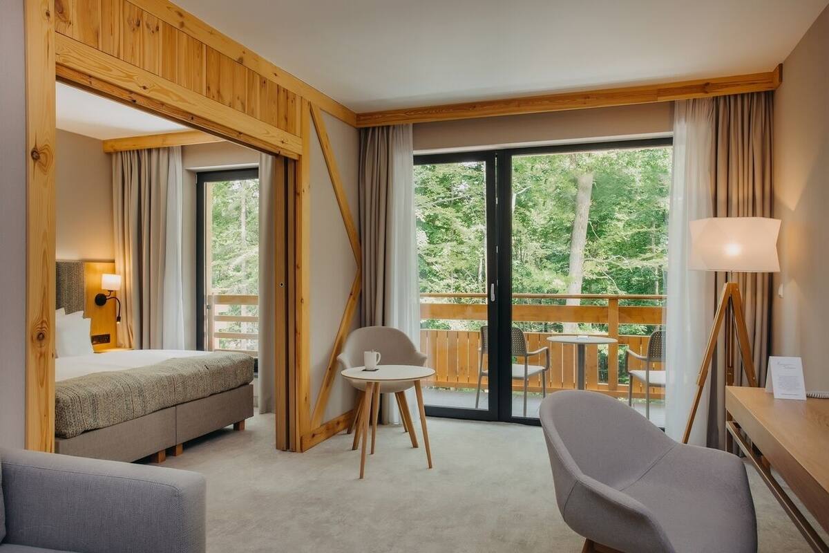 Een hotelkamer met een bed, een bureau, een stoel en een balkon met een tafel en stoelen.