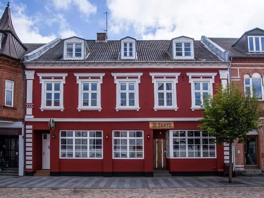 A red building with multiple windows and a sign that reads "TANTE".