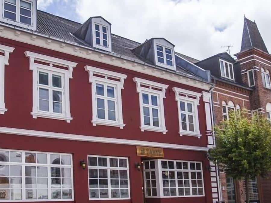 Un edificio rojo con marcos de ventanas blancos y una torre de ladrillo.