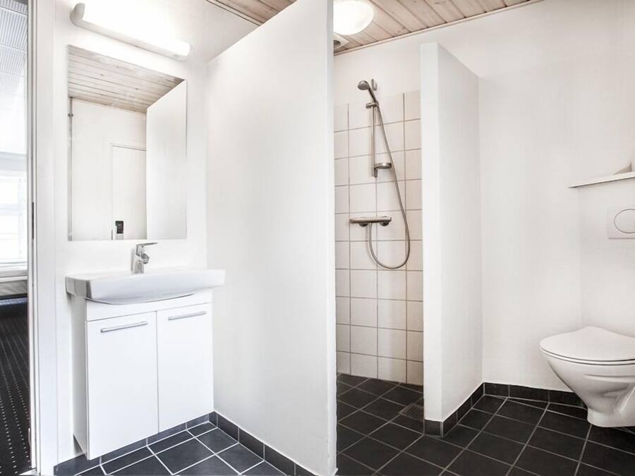 Un baño moderno con lavamanos, espejo y retrete blancos.