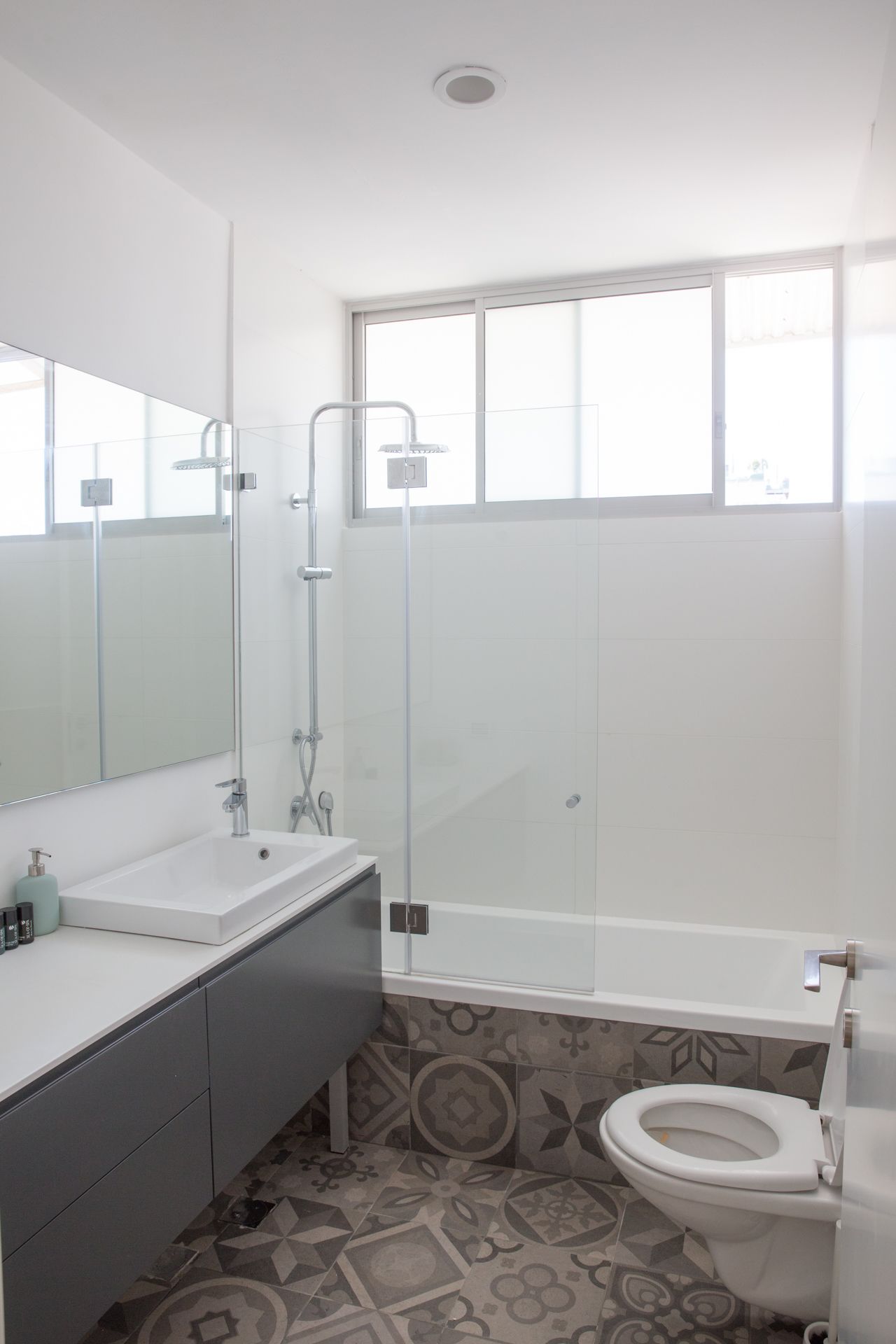 A modern bathroom with a glass-enclosed shower, a white sink, and a toilet.