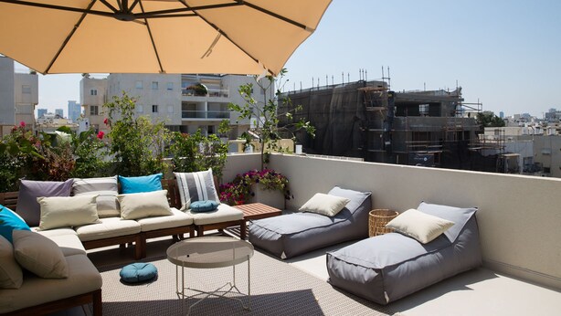 A rooftop terrace with outdoor seating, including a sofa and chairs, under a large umbrella. - Magic Penthouse TLV Harbor (Tel Aviv)
