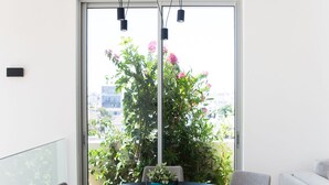 A modern dining area with a round table, four chairs, and a potted plant. - Magic Penthouse TLV Harbor (Tel Aviv)