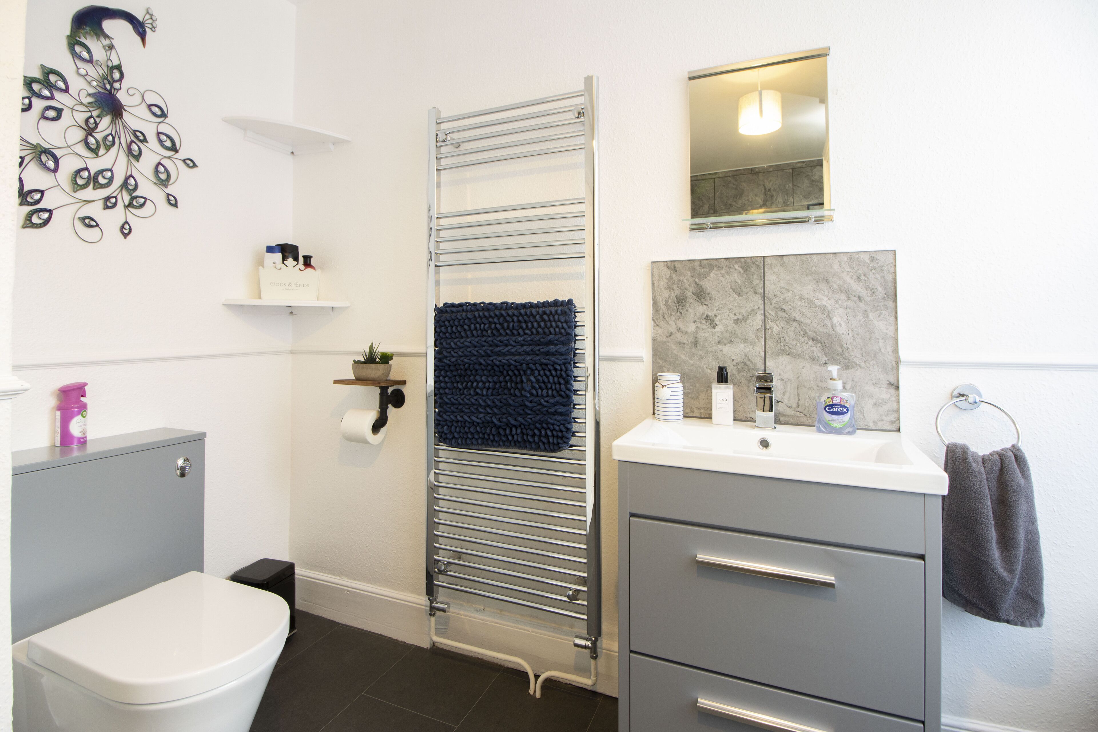 A modern bathroom with a toilet, a sink, a towel rack, and a shower area.