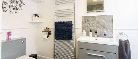 A modern bathroom with a toilet, a sink, a towel rack, and a shower area.
