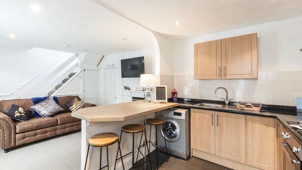 Une cuisine moderne dotée d’un îlot central, de meubles en bois et d’un lave-linge encastré.