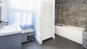 Une salle de bain moderne avec un meuble-lavabo blanc, un espace douche et une baignoire.