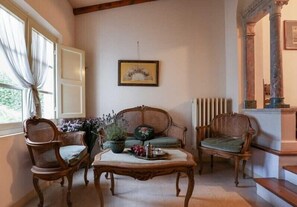 Um quarto aconchegante com um sofá de vime, duas cadeiras, uma mesa de centro de madeira e um quadro na parede.