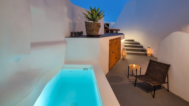 Un espacio de spa con una bañera, una silla de mimbre, una planta en maceta y una escalera.