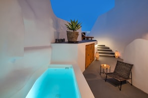 A spa area with a bathtub, a wicker chair, a potted plant, and a staircase.