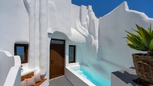 Un edificio de paredes blancas con una pequeña ventana, una puerta y un jacuzzi.