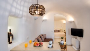 Una sala de estar moderna con comedor, un televisor montado en la pared y un rincón de estar acogedor.