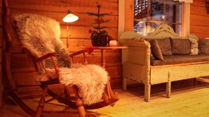 A cozy log cabin interior with a rocking chair, a sofa, and a table with a plant. - Isokenkäisten Klubi, Wilderness lodge (Kuusamo)