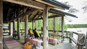 A wooden deck with benches and tables, overlooking a lake. - Isokenkäisten Klubi, Wilderness lodge (Kuusamo)