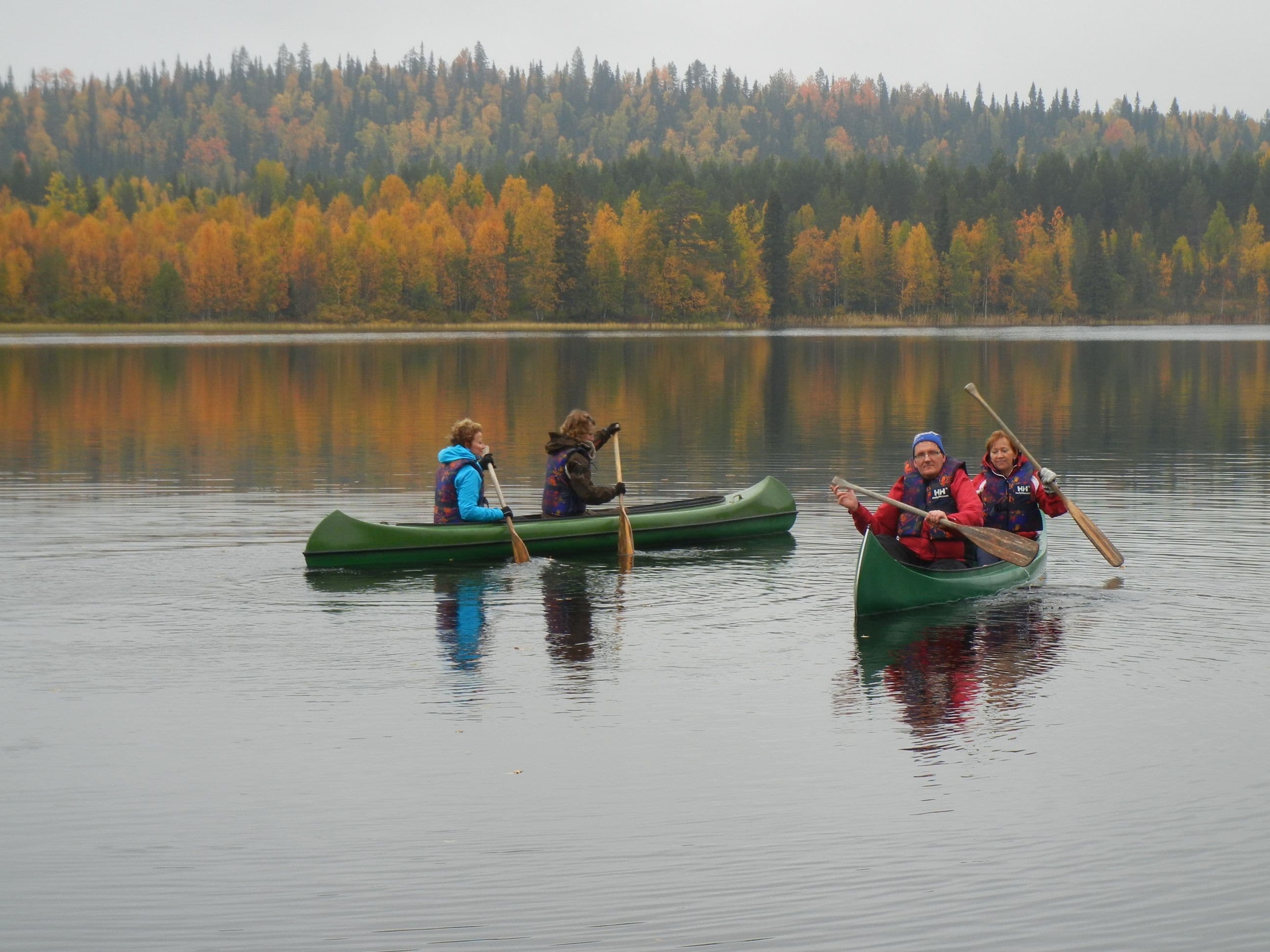 Three canoes on a calm lake with a forest in the background.