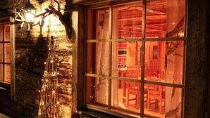 A rustic interior with a wooden wall, a bench, and a window with a view of a dining area. - Isokenkäisten Klubi, Wilderness lodge (Kuusamo)