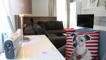 A living room with a sofa, a lamp, a TV, and a table with papers.