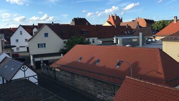 A view of a residential area with red-tiled roofs, a stone wall, and a white building with a sign that reads "amtmann".