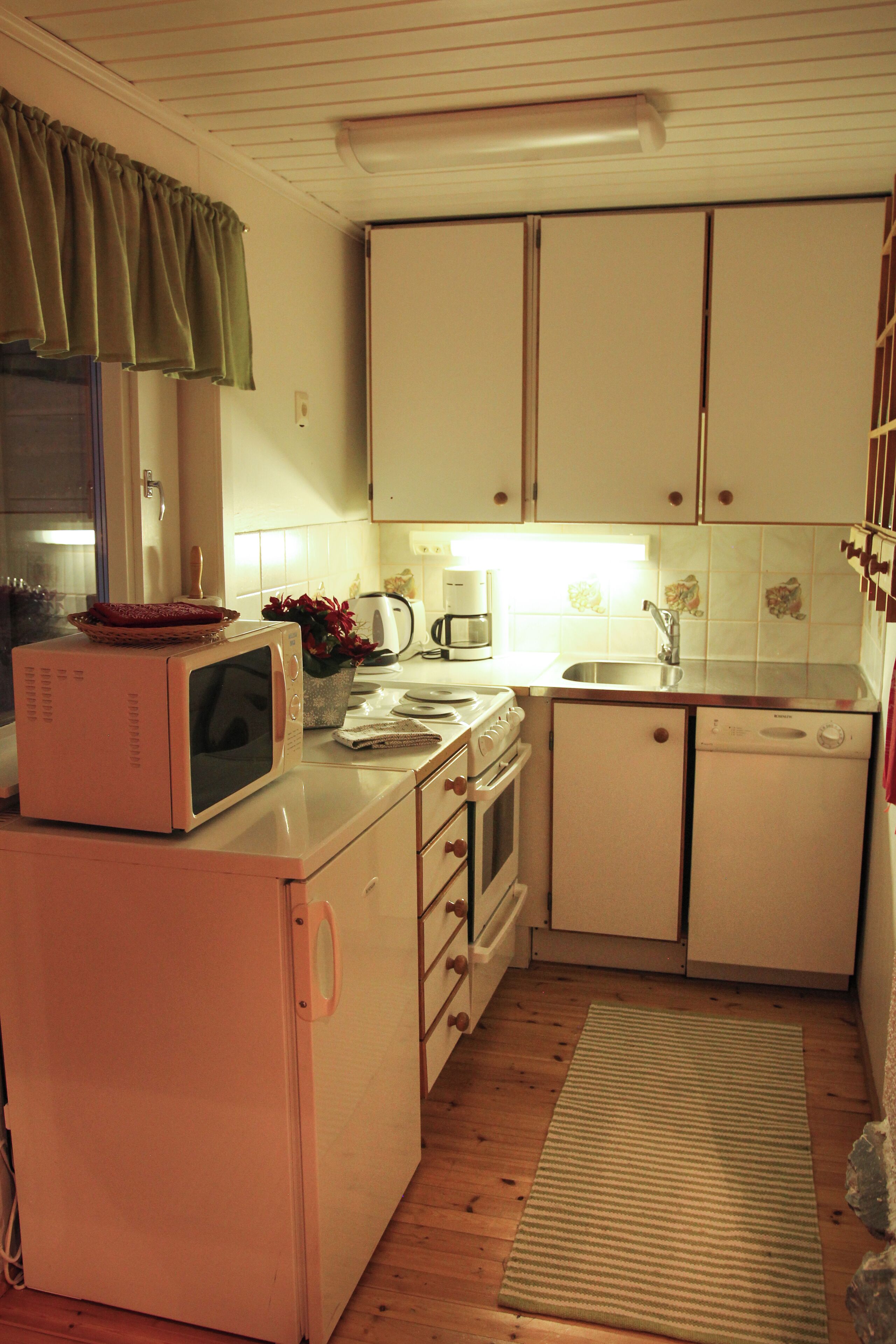 A compact kitchen with a microwave, stove, sink, and dishwasher.
