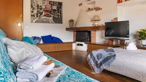 Un dormitorio moderno con sofá, cama, televisión, chimenea y estantería.