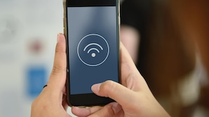 Una persona sosteniendo un teléfono inteligente que muestra un icono de señal Wi-Fi.