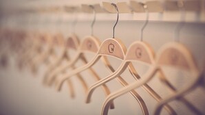 Una fila de perchas de madera con un logotipo, colgadas en un perchero.