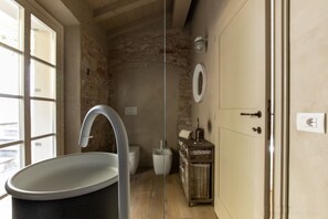 Une salle de bain avec un grand lavabo, des toilettes et un bidet. On y trouve un meuble en bois et une porte dotée d’une poignée.