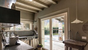 Una cocina con un ventanal grande, techo de madera y una mesa con jaulas de pájaros.
