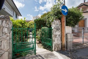 A gated entrance with a blue directional sign, stone walls, and a metal gate. - Il Covino (Viareggio)
