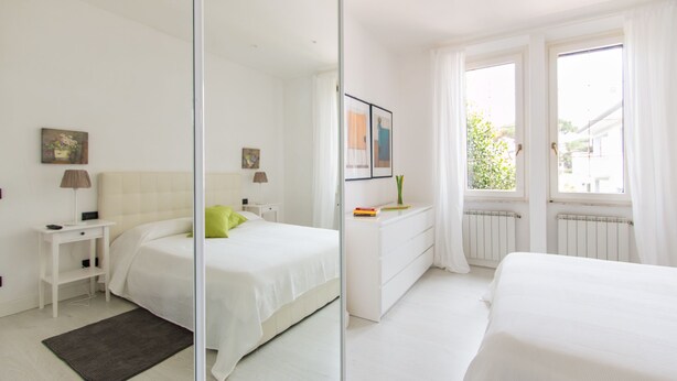 A modern bedroom with a bed, bedside table, dresser, and a large mirror. - Il Covino (Viareggio)