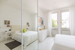 A modern bedroom with a bed, bedside table, dresser, and a large mirror. - Il Covino (Viareggio)