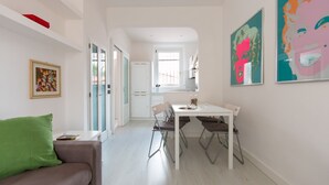 A modern kitchen with white cabinets, a dining table with four chairs, and a window providing natural light. - Il Covino (Viareggio)